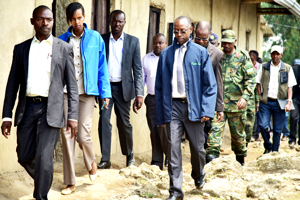 Officials walk past the old classrooms at Kanyove school 