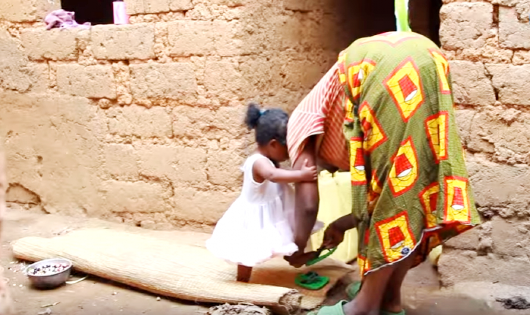 Mother helping daughter to wear shoes 